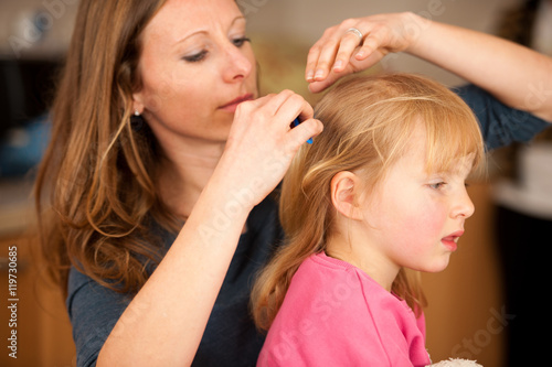 Mother combs hair to a little girl