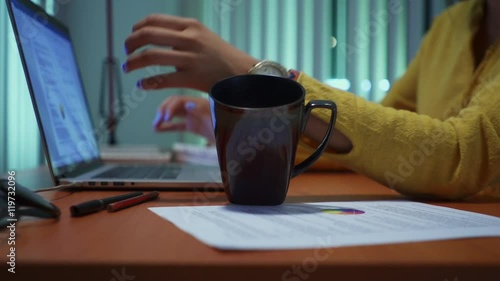Young beautiful hispanic woman spilling coffee on papers while working with laptop pc at home, girl studying late at night, female college student doing homework for school. Slow motion