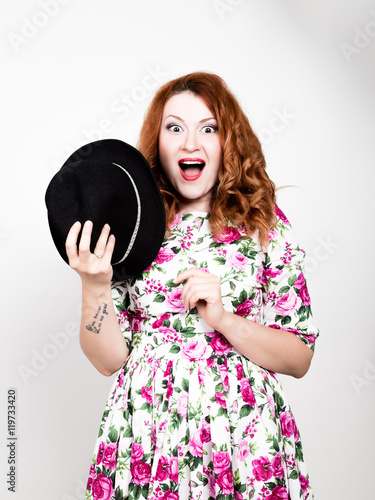 young stylish red-haired woman with curly hair and pretty face holds a black hat. expresses different emotions