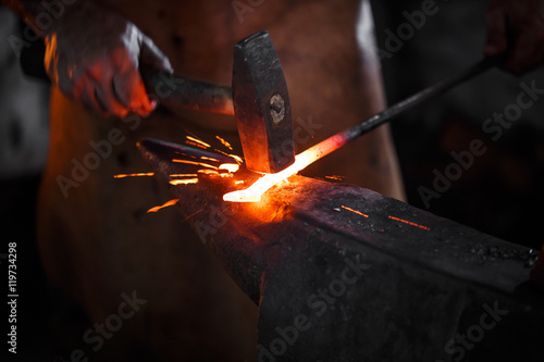 Fotografering Blacksmith manually forging the molten metal