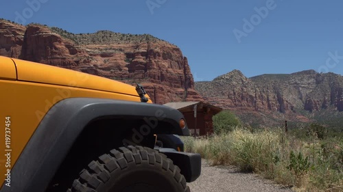 Offroad SUV parked in front of red rock mountains of Sedona, strong yellow color of the safari jeep stands out against nature scenic