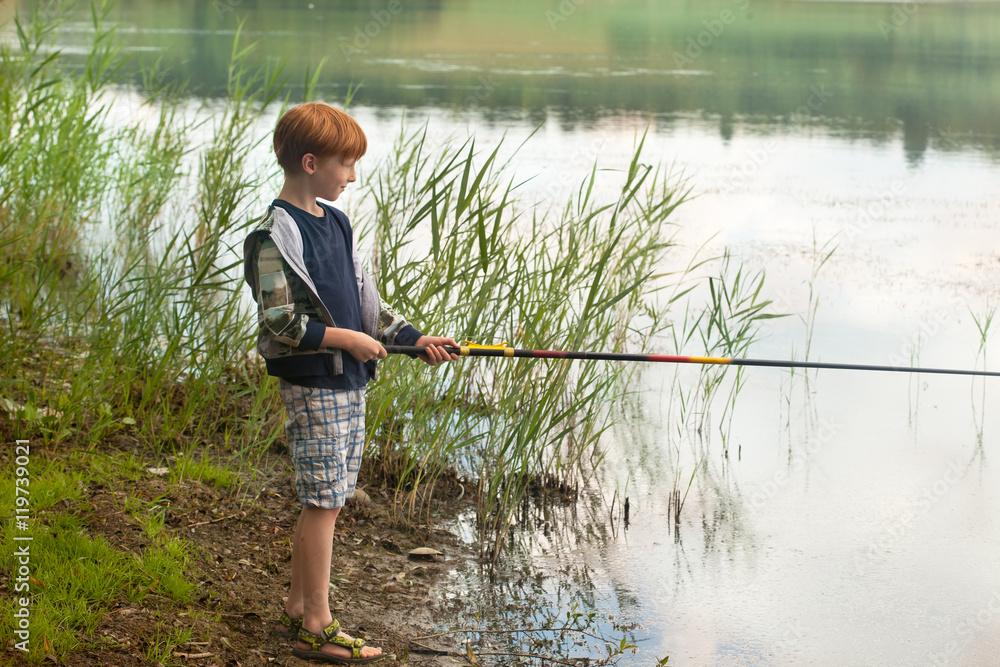 Little boy with fishing rod on a lake shore Little boy with fishing rod on a lake shore