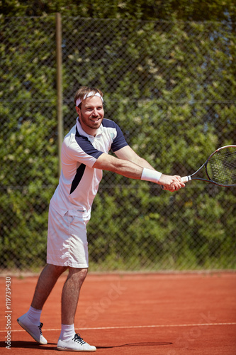 Man with racket on tennis court © luckybusiness