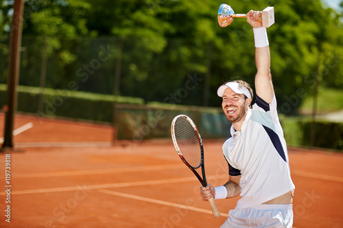 Happy tennis player with goblet and racket © luckybusiness