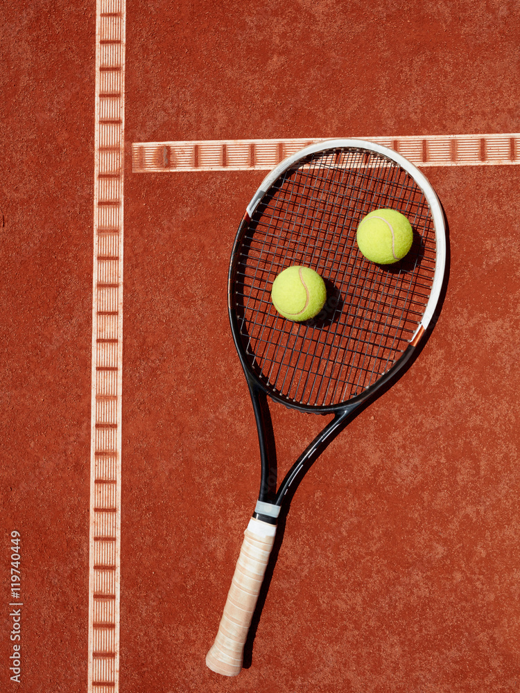 Close up of tennis racket and yellow balls at red clay