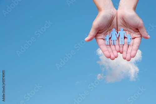 Paper family in hands on blue sky background welfare concept