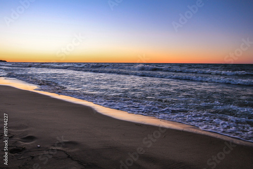 Sunset Beach Panorama. Waves crash on the wide sandy beaches of Lake Huron with a sunset sky at the horizon.
