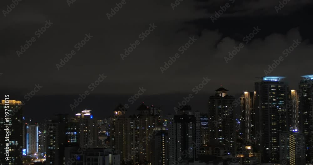 In Kuala Lumpur, Malaysia seen night city with skyscrapers than seen pool on roof of a hotel and woman working on tablet In Kuala Lumpur, Malaysia seen night city with skyscrapers than seen pool on roof of a hotel and woman working on tablet