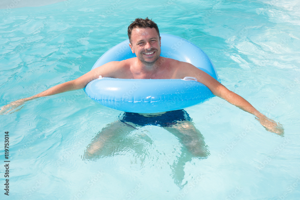 man relaxing on the air buoy in the swimming pool. concept about vacation and free time