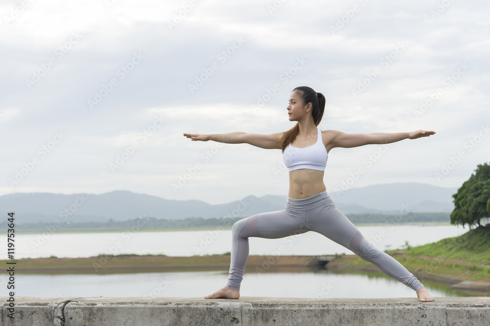 Woman practicing Yoga Warrior pose in morning.