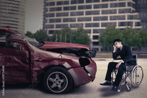Disabled person with damaged car looks sad © Creativa Images