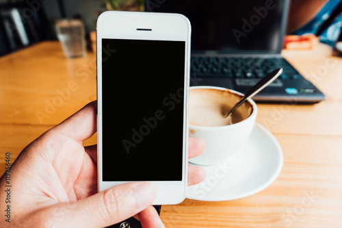 Businessman hand holding a phone with white screen against the b