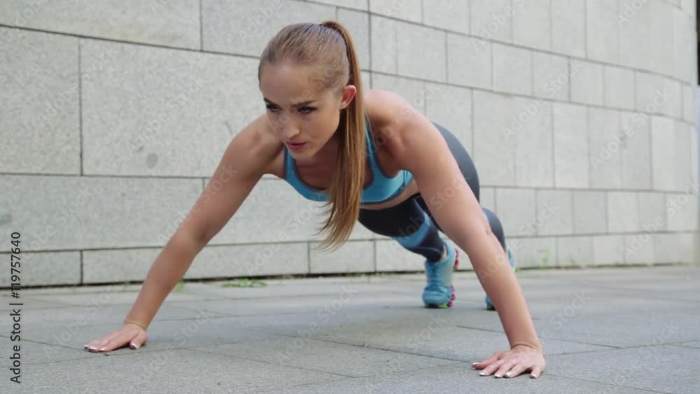 Young pretty woman doing fitness push-ups sport exercises on grey background. Young pretty woman doing fitness push-ups sport exercises on grey background.