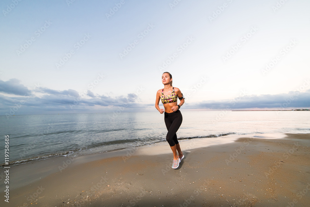 Cute fit girl running on beach at sunrise Cute fit girl running on beach at sunrise