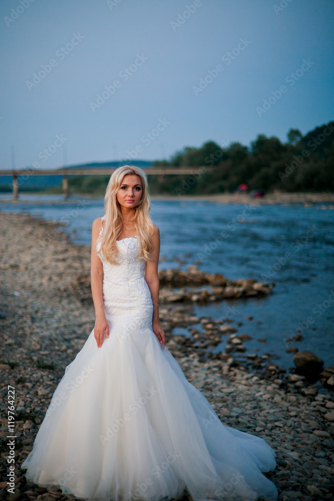 Wonderful bride in amazing white dress on mountain river's coast
