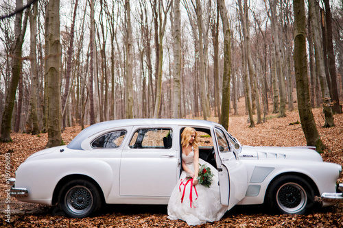 Beautiful happy bride is sitting in white retro car photo