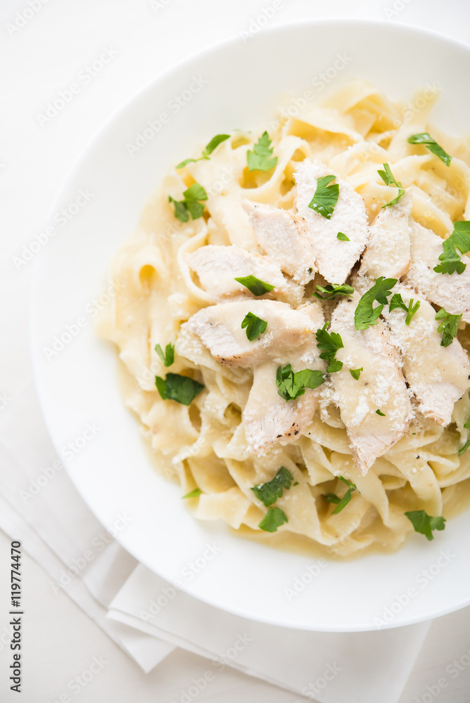 Pasta fettuccine alfredo with chicken, parmesan and parsley on white background top view. Italian cuisine. Pasta fettuccine alfredo with chicken, parmesan and parsley on white background top view. Italian cuisine.