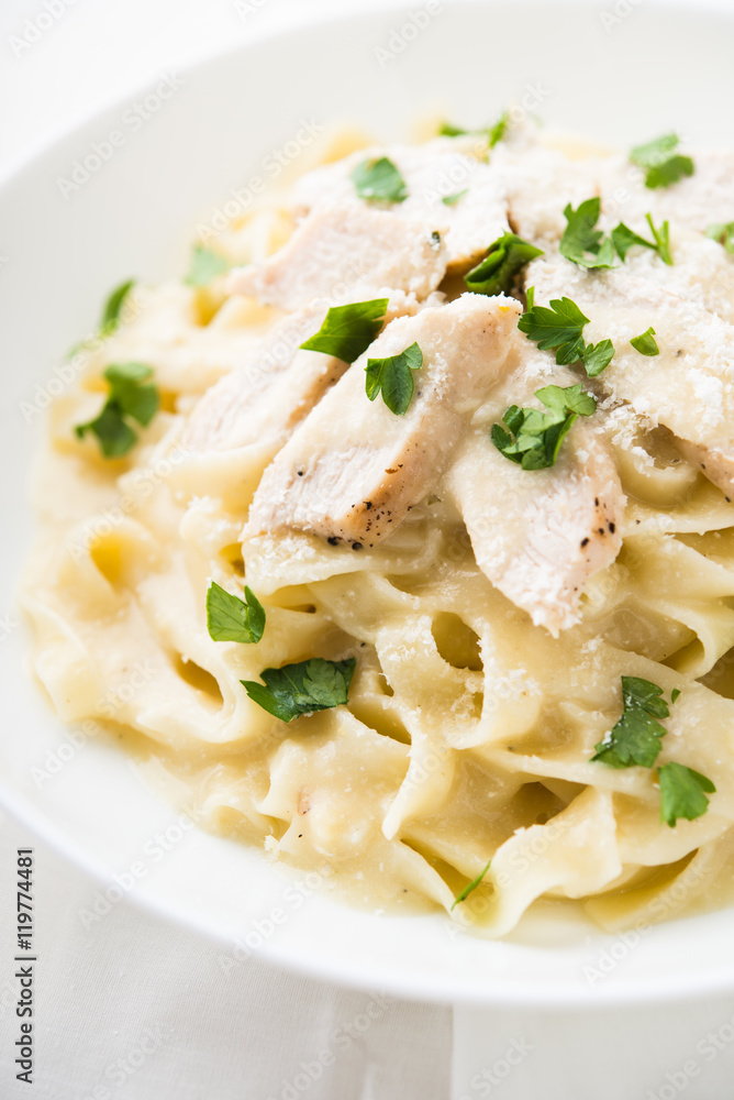 Pasta fettuccine alfredo with chicken, parmesan and parsley on white background close up. Italian cuisine. Pasta fettuccine alfredo with chicken, parmesan and parsley on white background close up. Italian cuisine.