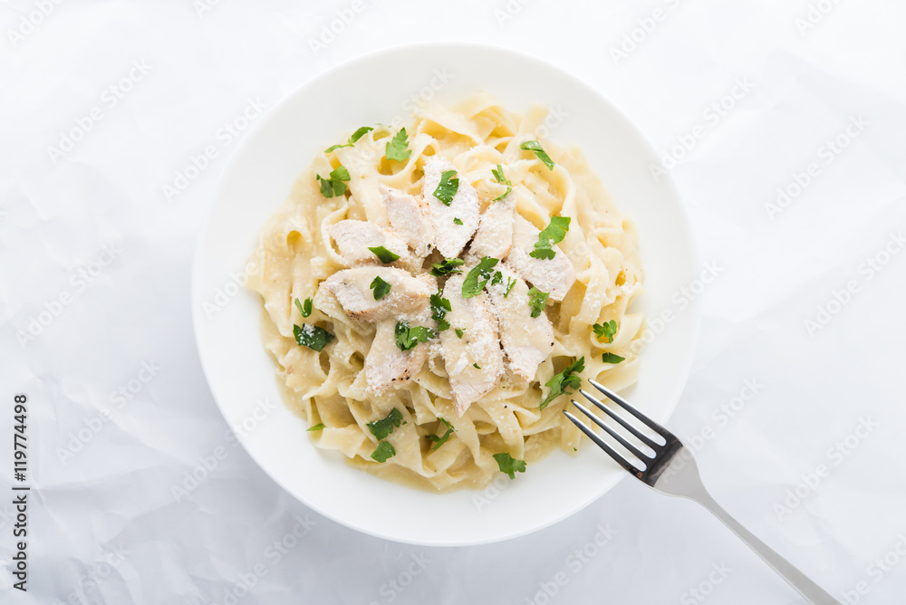 Pasta fettuccine alfredo with chicken, parmesan and parsley on white background top view. Italian cuisine. Pasta fettuccine alfredo with chicken, parmesan and parsley on white background top view. Italian cuisine.