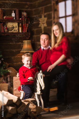 Young pregnant mother, father and small son celebrating Christmas at home