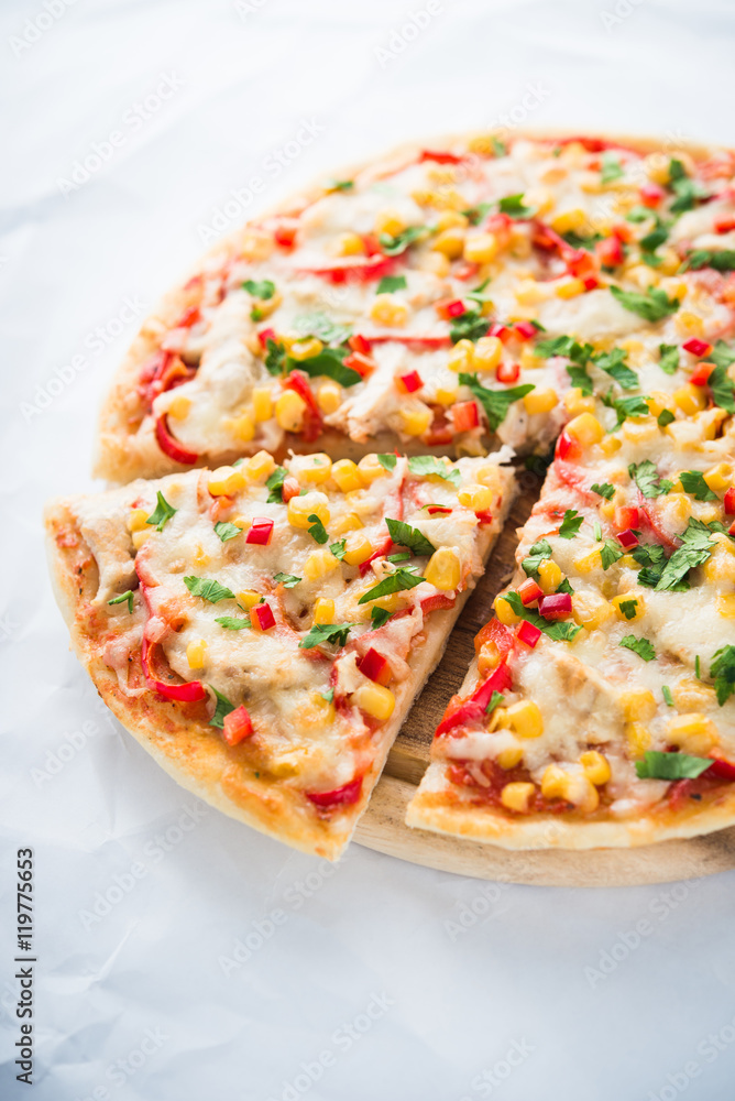 Sliced pizza with mozzarella cheese, chicken, sweet corn, sweet pepper and parsley on white background close up. Italian cuisine. Sliced pizza with mozzarella cheese, chicken, sweet corn, sweet pepper and parsley on white background close up. Italian cuisine.