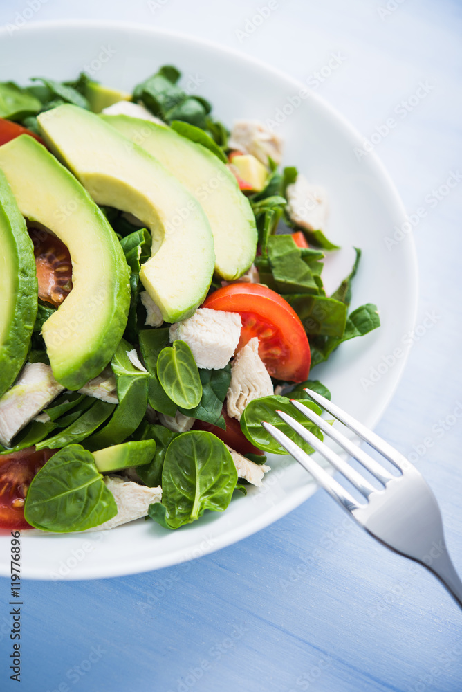 Fresh salad with chicken, tomatoes, spinach and avocado on blue wooden background close up. Healthy food. Fresh salad with chicken, tomatoes, spinach and avocado on blue wooden background close up. Healthy food.