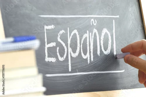 Obraz Ręczne pisanie na tablicy w klasie językowej z napisem „hiszpański”. Niektóre książki i materiały szkolne.