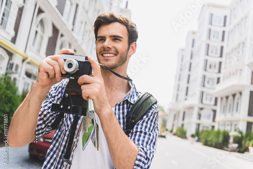 Joyful young man photographing urban architecture