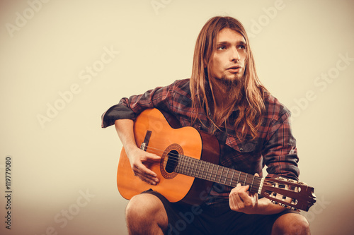 Sitting man playing guitar.