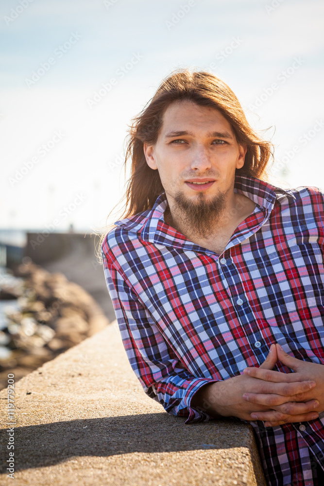 Man long hair relaxing by seaside