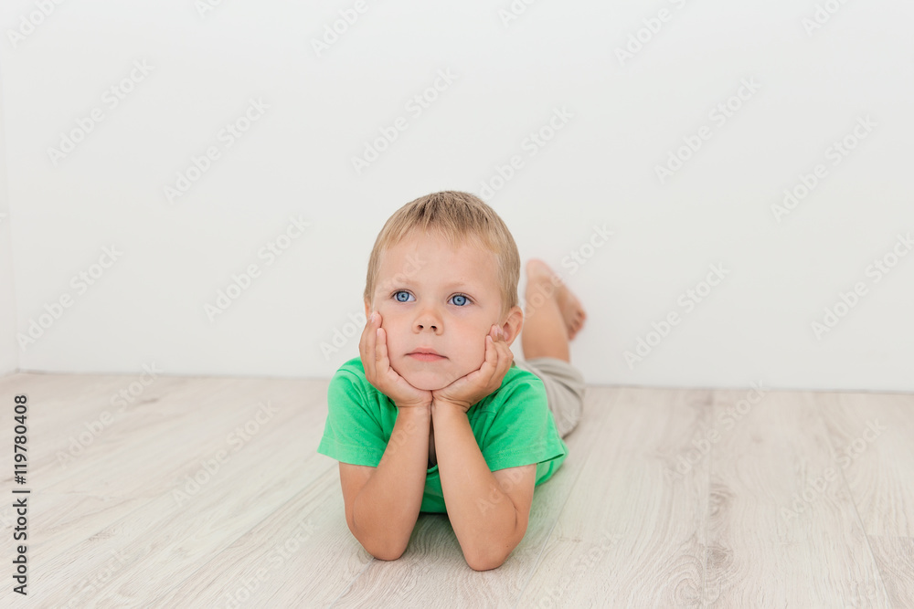 Little handsome boy with blue eyes lying on the floor Little handsome boy with blue eyes lying on the floor