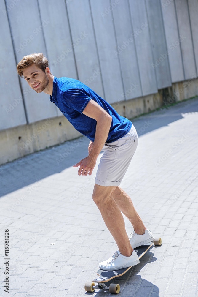 Fototapeta premium Joyful guy riding skate outdoors