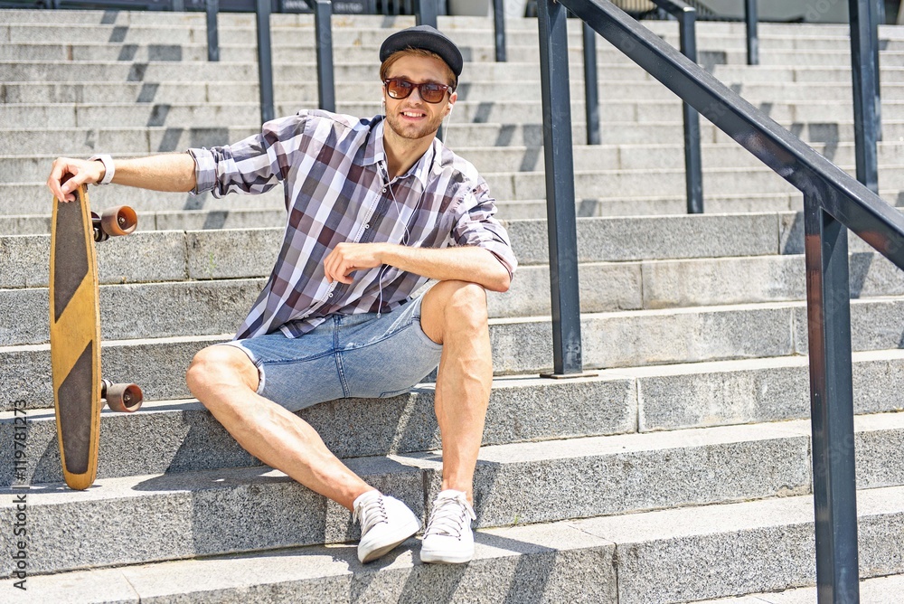 Carefree male skater sitting on stairs