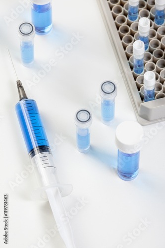 Vials in rack and syringe containing blue liquid
