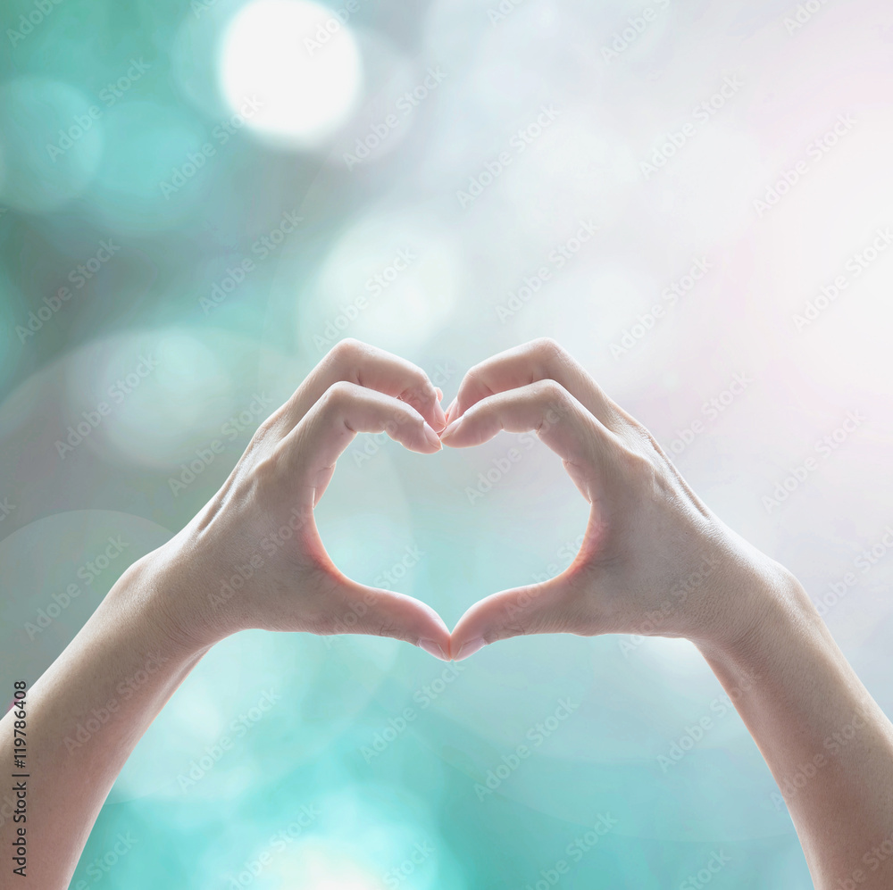 Fototapeta premium Healthy human hand in heart shape showing love friendship on blurred abstract cool blue green sky color bokeh background: Global eco environment CSR natural resource awareness/ concept/ campaign/ idea