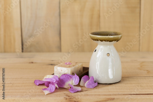 Ceramic burner and natural soap bar with rose flower leaf on wood background
