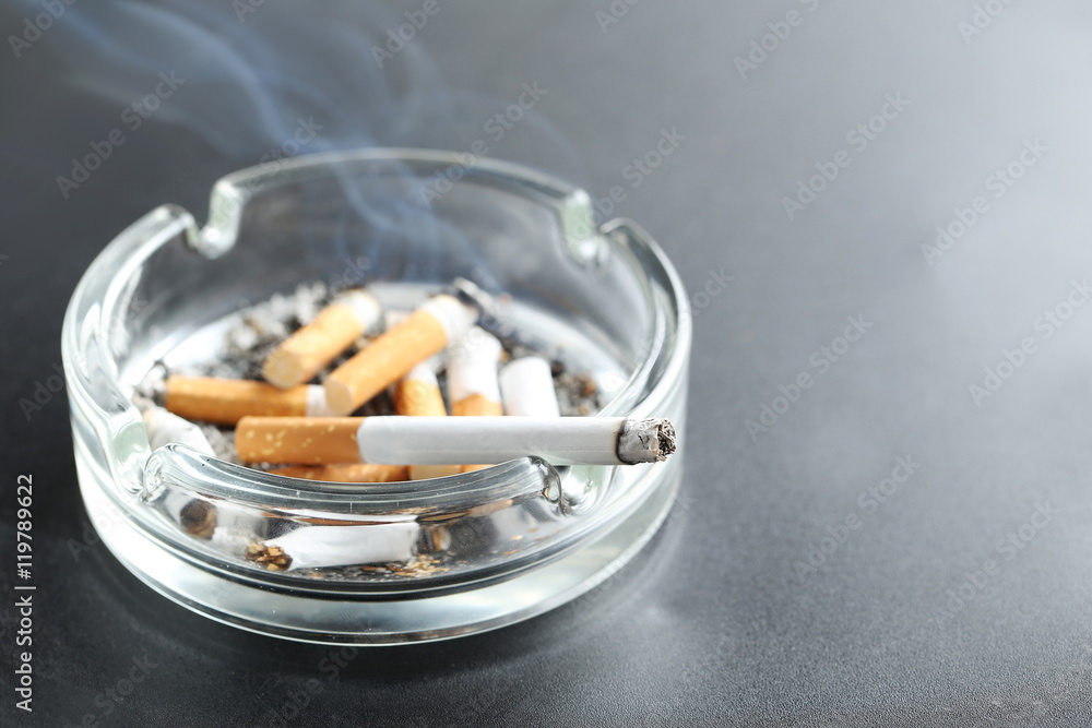 Cigarette butts with ash in ashtray on black background Cigarette butts with ash in ashtray on black background