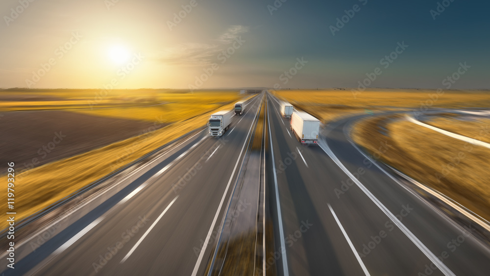 Speed concept with trucks on the highway at idyllic sunset