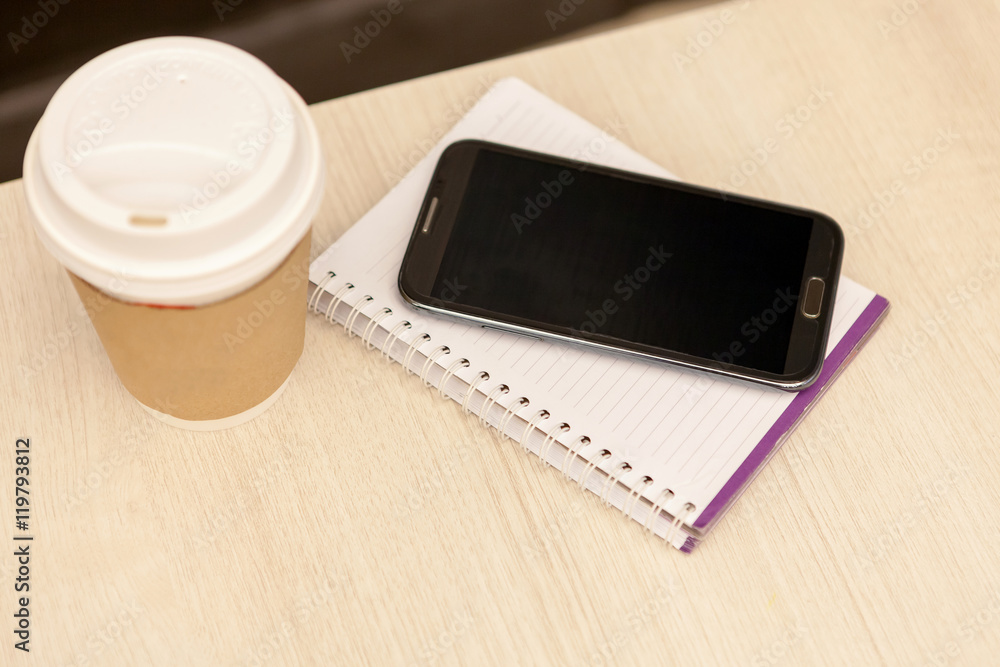 Smart phone with notebook and cup of strong coffee on wooden background. Cellphone with writing set with espresso Smart phone with notebook and cup of strong coffee on wooden background. Cellphone with writing set with espresso