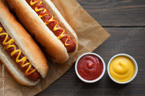 Barbecue Grilled Hot Dog with Yellow Mustard and ketchup on wooden table. Fast food. photo
