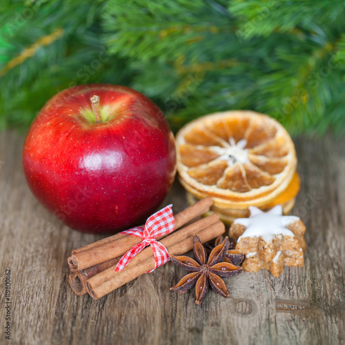 Roter Apfel, Orangenscheiben, Zimtstangen, Anissterne und Weihnachtsgebäck auf altem Holz - Weihnachten