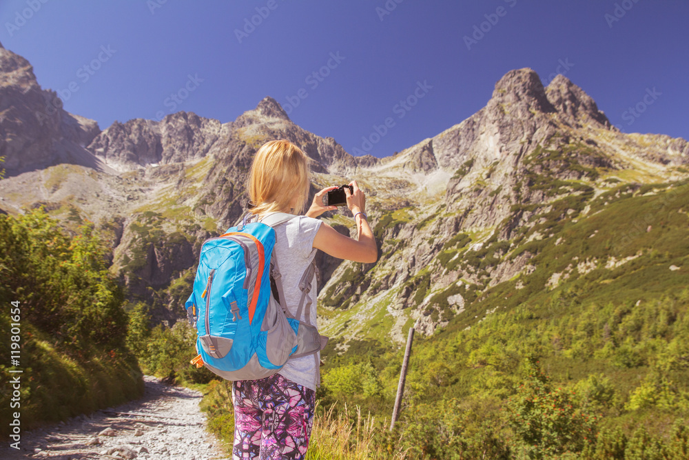 Young woman backpacker taking photographs