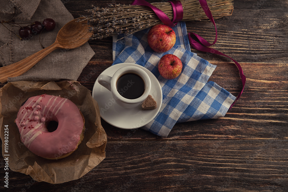 fresh donut with coffee on wooden table with napkin, spoon and c