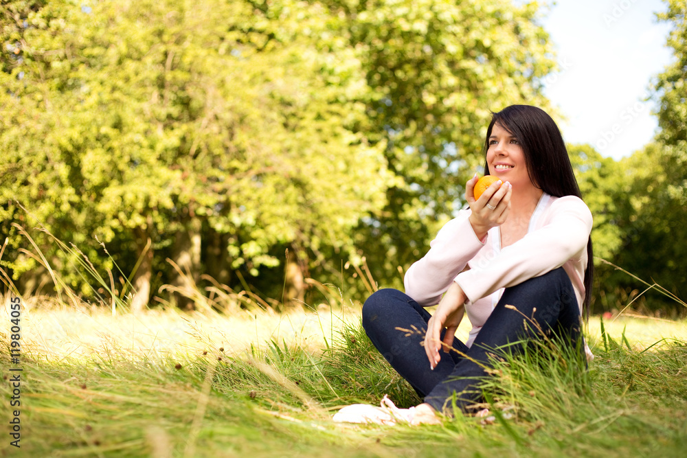 young woman sitting in the park holding an orange young woman sitting in the park holding an orange