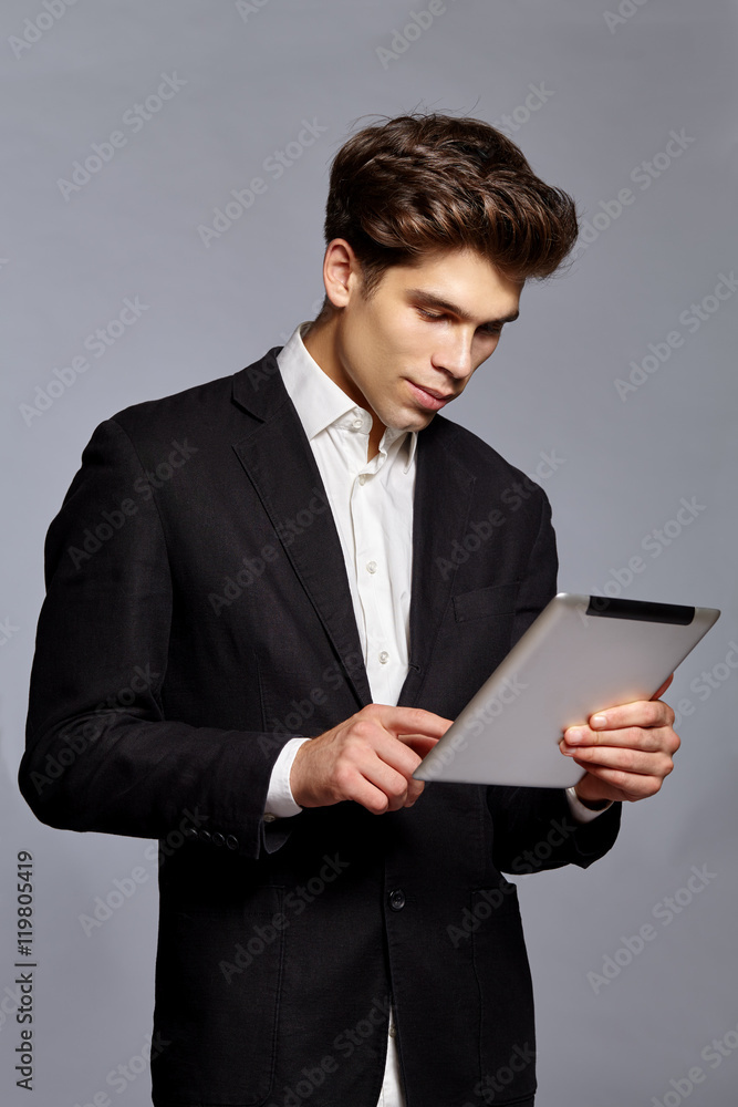 Guy with hairstyle holding tablet and working on it Guy with hairstyle holding tablet and working on it