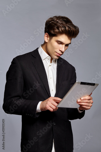 Guy with hairstyle holding tablet and working on it