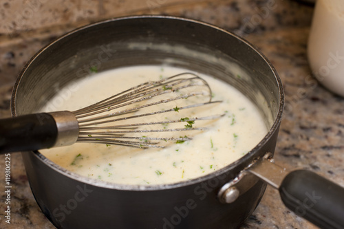 Pot of bechamel sauce with a whisk photo