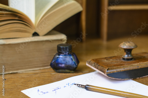 Text “Once upon a time” handwritten in ink surrounded with a fountain pen, an ink pot, a blotting paper holder and old books.