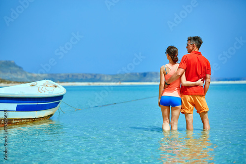 couple standing in the sea near the boat. They hold each other's hands
