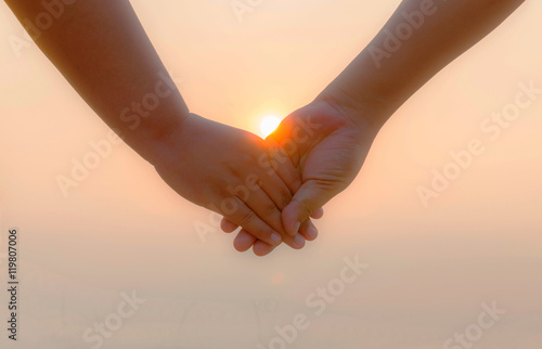 Romantic couple with clasped hands backlit by a bright evening s